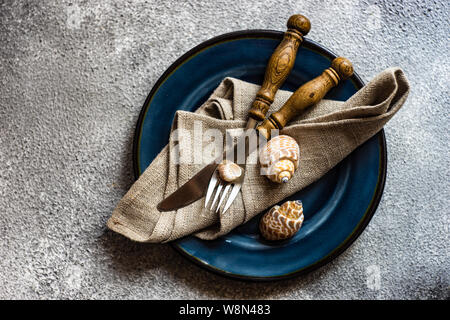 Marine cutlery set with shells and sea stars on grey concrete background with copy space Stock Photo