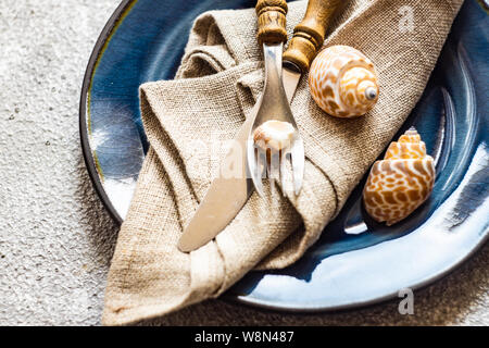 Marine cutlery set with shells and sea stars on grey concrete background with copy space Stock Photo