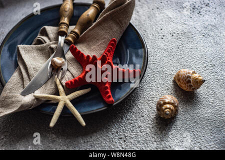 Marine cutlery set with shells and sea stars on grey concrete background with copy space Stock Photo