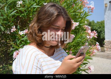 Young woman outdoors, checking messages on her mobile phone Stock Photo