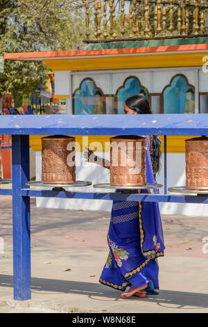 A young Indian woman spins Buddhist prayer wheels at the Mulagandha Kuti Vihara temple in Sarnath, Uttar Pradesh, India, Asia, South Asia Stock Photo