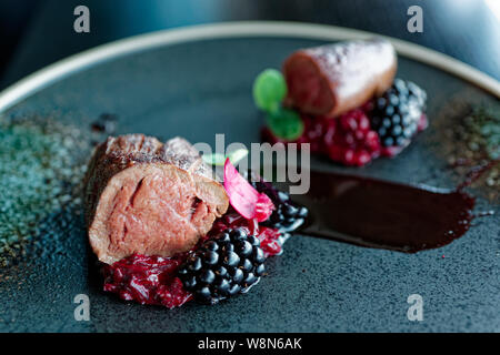 Venison fillet with beetroot carpaccio and blackberries on dark plate Stock Photo