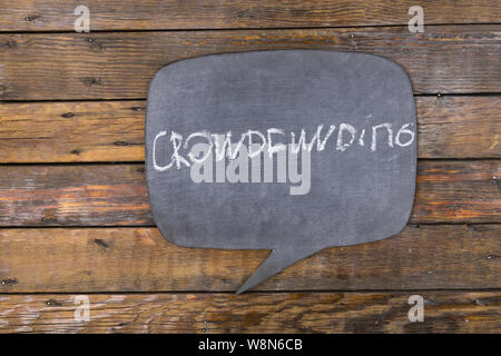 Word, inscription CROWDFUNDING written in chalk on a blackboard made in the form of thought. Top view. Stock Photo