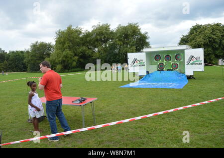 little children geting teach  how to shoot on target event in Manchester with people standing having fun Stock Photo