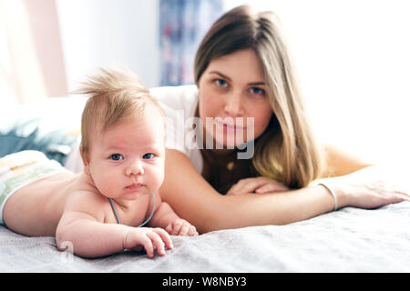 Mother and newborn baby in a diaper lie on the bed in the bedroom Stock Photo