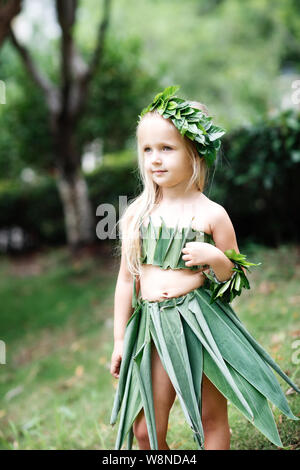 Cute little blonde girl in carnival costume made of green grass outdoor. kid ready for halloween party Stock Photo