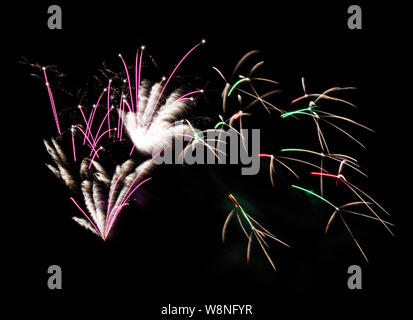 Fireworks display of pink, green and white fireworks fill the sky during a show on a summer night. Stock Photo