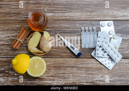 Ginger, lemon, honey and  different drugs  with thermometer on wooden table.Alternative remedies and traditional pills to treat colds and flu. Natural Stock Photo