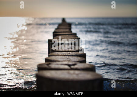 Groynes in the Baltic Sea. They serve as a coastal defense. Beautiful sunset over the ocean with old wooden wave breakers. Stock Photo