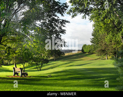 Park bench and small rolling hills in Burnet Park, leading down to the Western Lights neighborhood of Syracuse, New York on a beautiful summer morning Stock Photo