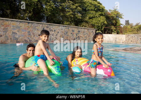 Family playing in a swimming pool Stock Photo