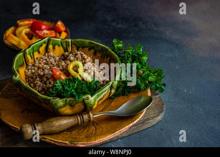 Keto diet concept with boiled buckwheat seeds and vegetables in a rustic bowl on stone background with copyspace Stock Photo