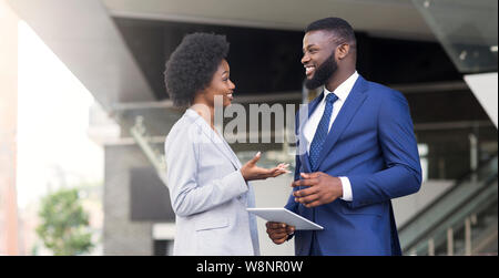 Two coworkers with digital tablet, discussing new project outdoors Stock Photo