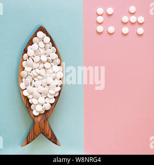 Calcium pills in a wooden dish in the form of a fish. Fish is rich in calcium. Color background. Word of CA (calcium) is laid out by pills. Flay lay Stock Photo