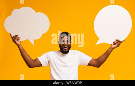 Young man having complex choice holding two speech bubbles Stock Photo
