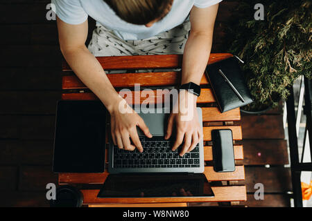 From above crop man sitting at desk in cafe and typing on laptop Stock Photo