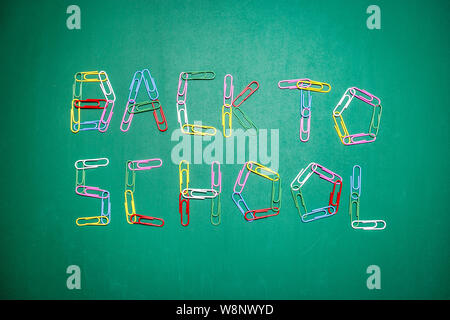 Background with the words back to school written with multicolored paper clips on green chalkboard. Back to school concept. Stock Photo