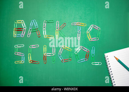Background with the words back to school written with multicolored paper clips on green chalkboard. Back to school concept. Stock Photo