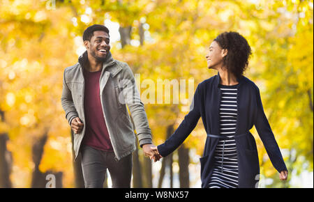 Happy couple running together in autumn park Stock Photo