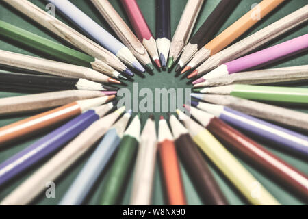 Many different colored pencils on chalkboard background. Close-up with selective focus. Vintage toned photo. Stock Photo