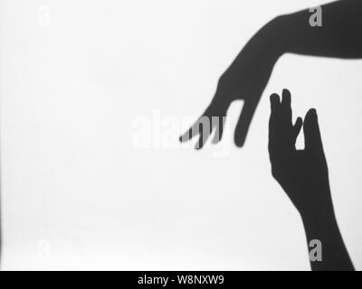 two women's hands reach for each other. Helping hand silhouette, female and male together. Stock Photo