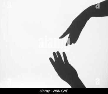 two women's hands reach for each other. Helping hand silhouette, female and male together. Stock Photo