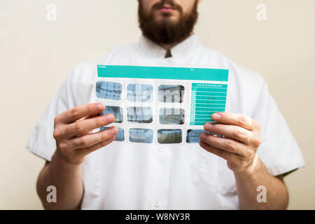 Image of male doctor or dentist holding and looking at old dental x-ray, analyzing Stock Photo