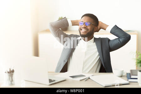 African businessman resting at office, sitting with hands behind head Stock Photo