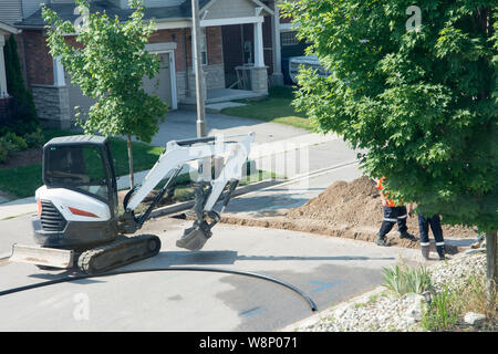 cable laying with optical fiber through a trench dug through an asphalt road Stock Photo