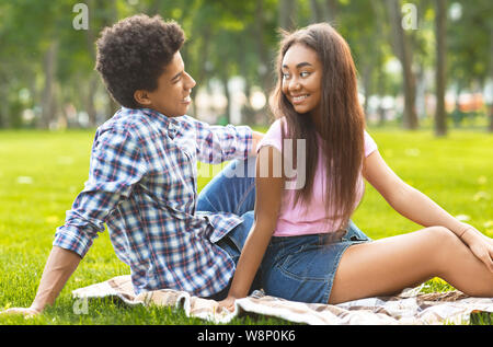 Happy teenage couple resting in park, looking at each other Stock Photo