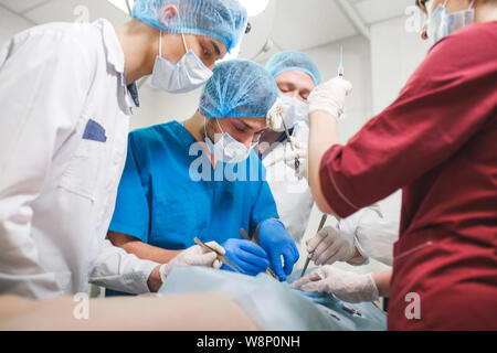 Group of surgeons at work operating in surgical theatre. Resuscitation medicine team wearing protective masks Stock Photo