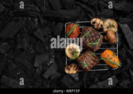 Grilled meat steaks with vegetables on grid prepared on coal Stock Photo