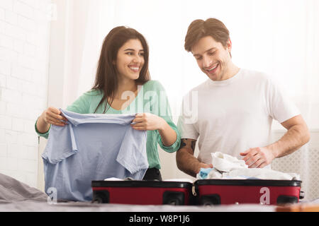 Happy couple preparing for honeymoon, folding clothes