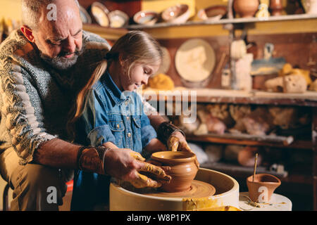 Pottery workshop. Grandpa teaches granddaughter pottery. Clay modeling Stock Photo