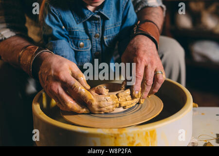 Pottery workshop. Grandpa teaches granddaughter pottery. Clay modeling Stock Photo