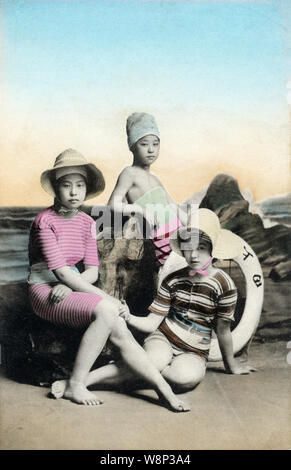 [ 1910s Japan - Japanese Women in Bathing Suit ] —   A studio photo of three young Japanese women wearing modern hats posing in bathing suits. Models for these kind of photos were almost always geisha.  20th century vintage postcard. Stock Photo