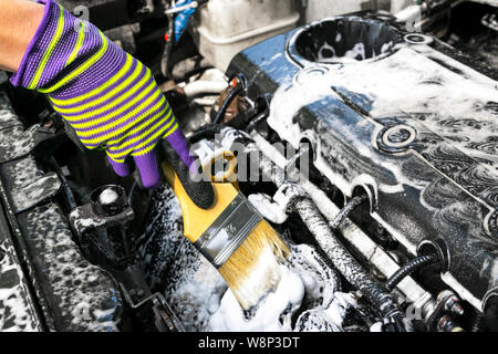 A man cleaning car engine with shampoo and brush. Car detailing or valeting concept. Selective focus. Car detailing. Cleaning with sponge. Worker clea Stock Photo