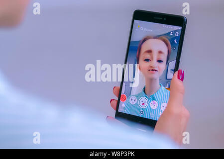 Woman using Snapchat multimedia messaging app with face mask on smartphone Stock Photo