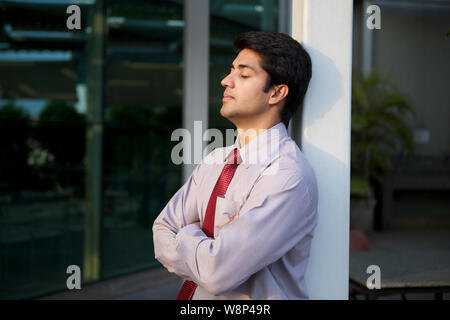 Businessman leaning against pole Stock Photo