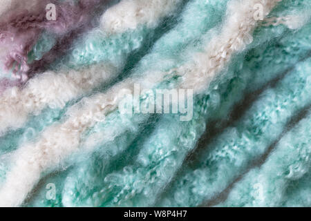 Woolen fluffy threads or tassels from scarf, macro. Soft pastel colors merino wool backdrop, closeup. Autumn and winter flat lay. Scandinavian minimal Stock Photo