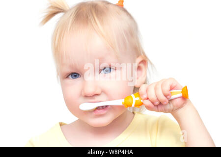 Little beautiful girl with blue eyes and pigtails brushes her teeth on a white background, close-up Stock Photo