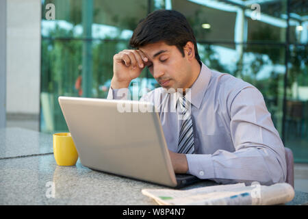 Businessman working on a laptop and looking stressed Stock Photo