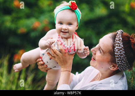 happy harmonious family outdoors. mother throws baby up, laughing and playing in the summer on the nature. Stock Photo