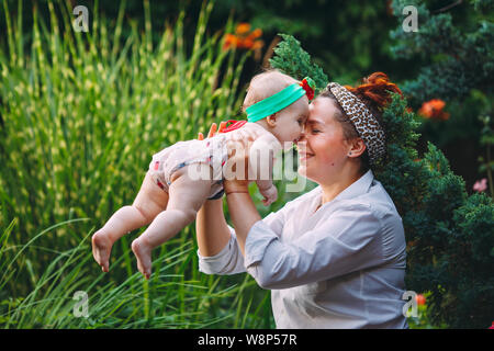 happy harmonious family outdoors. mother throws baby up, laughing and playing in the summer on the nature. Stock Photo