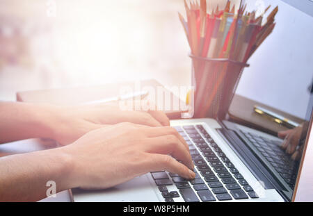 Close up of male hands using Laptop on the desk, toned with sunlight Stock Photo