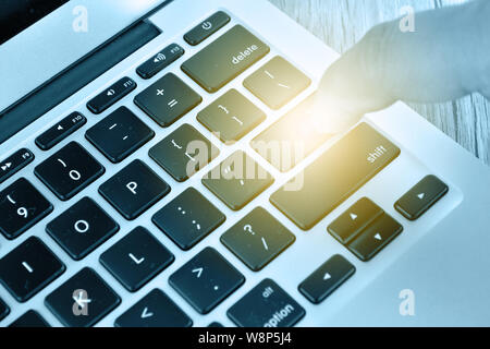 Hand touching laptop computer keyboard - Focus on the keyboard Stock Photo