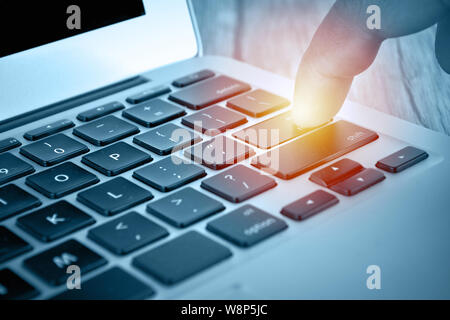 Hand touching laptop computer keyboard - Focus on the keyboard Stock Photo