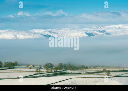 Shap Fells rising above a blanket of mist on a snowy morning, Cumbria, UK Stock Photo
