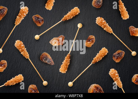 Flat lay brown sugar on a stick  as pattern on black slate background. Top view Stock Photo
