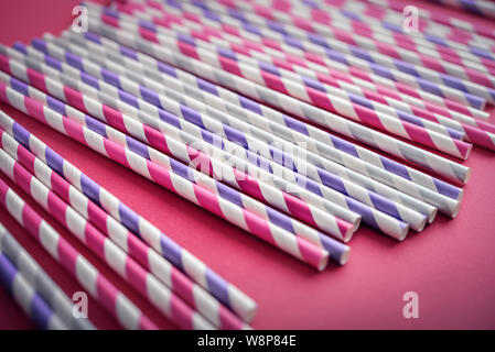 Colorful drinking striped straws on pink background closeup Stock Photo